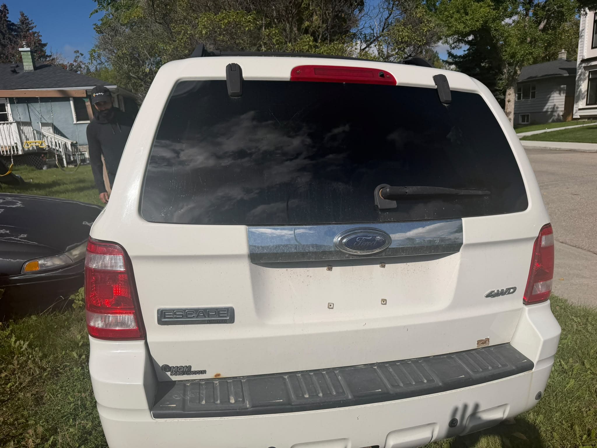 White Ford Escape awaiting junk car collection in Calgary