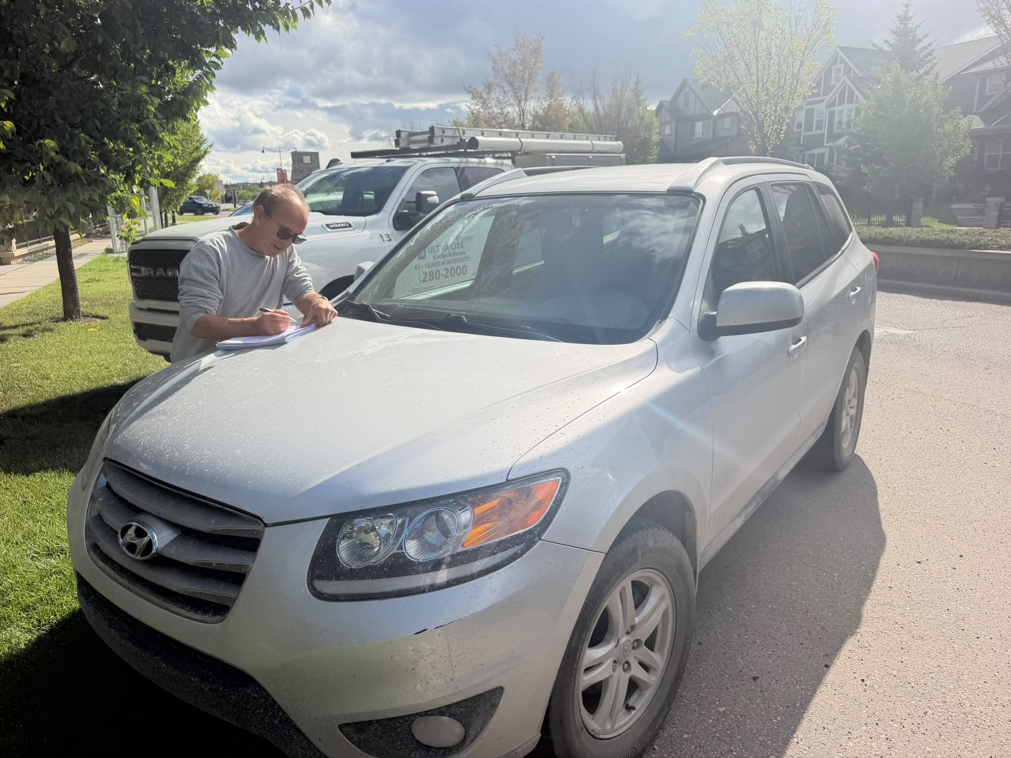 Owner signing paperwork beside a white Hyundai in Calgary